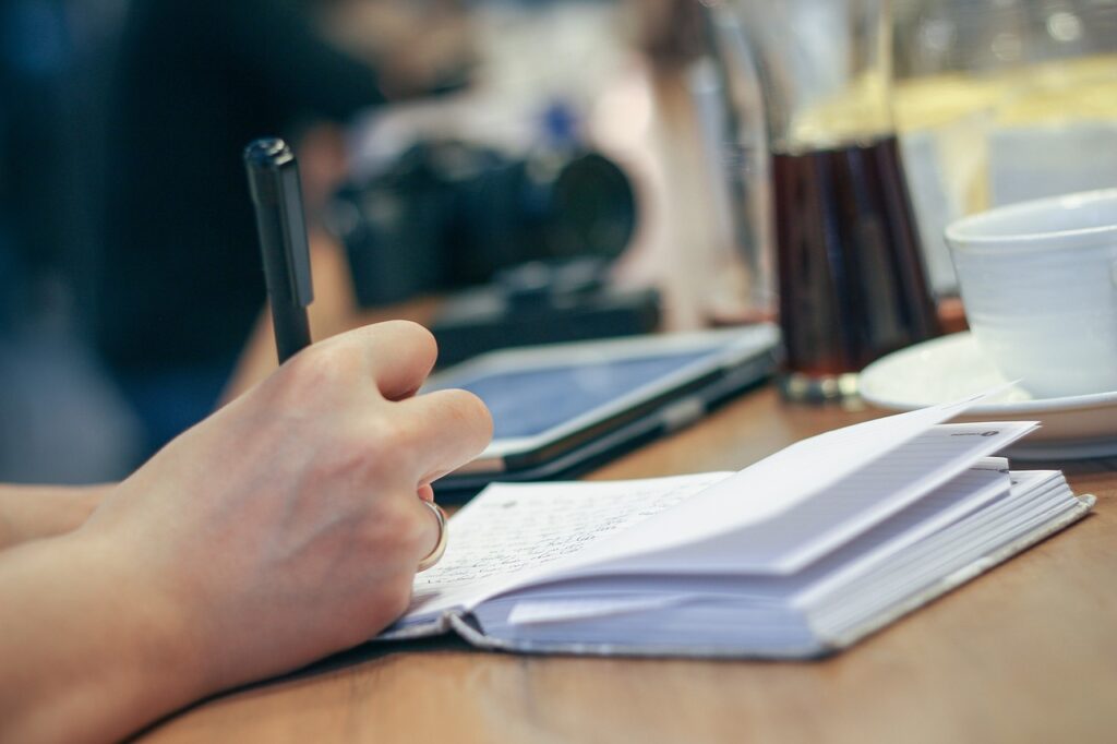 Journaling prompts for creativity: A man writes in his journal at a coffee shop