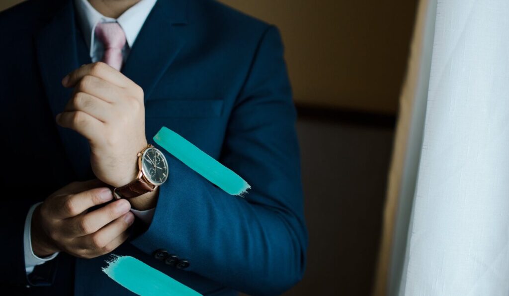 A professional man in a suit and tie, straightens his cuff, revealing a nice looking watch. He is representing career success through journaling